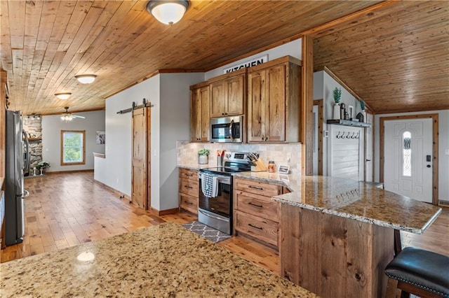 kitchen with stainless steel appliances, a barn door, wood ceiling, and decorative backsplash