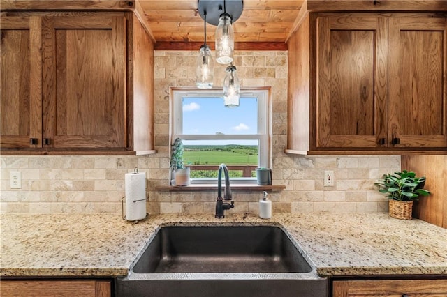 kitchen with sink, wood ceiling, hanging light fixtures, light stone countertops, and decorative backsplash