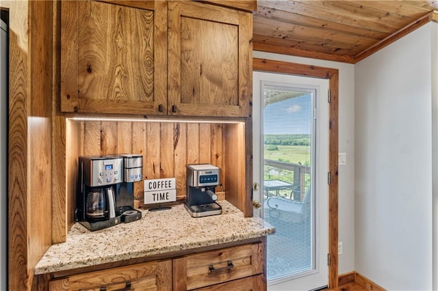 kitchen featuring ornamental molding, wooden ceiling, and light stone counters