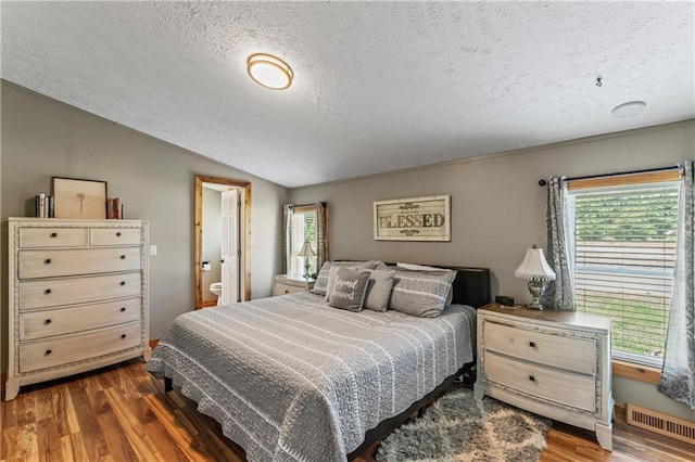 bedroom featuring dark wood-type flooring, vaulted ceiling, and a textured ceiling