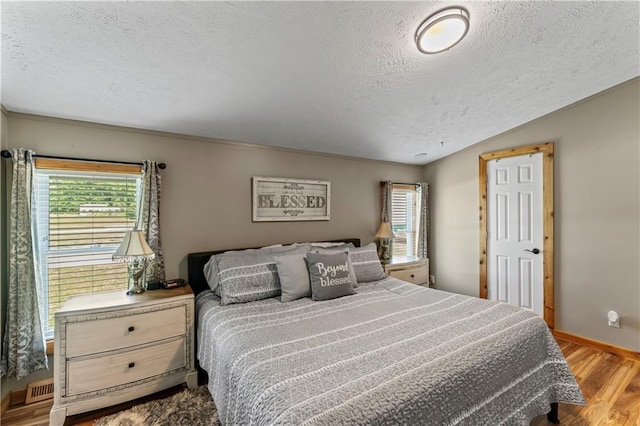 bedroom with light hardwood / wood-style floors and a textured ceiling