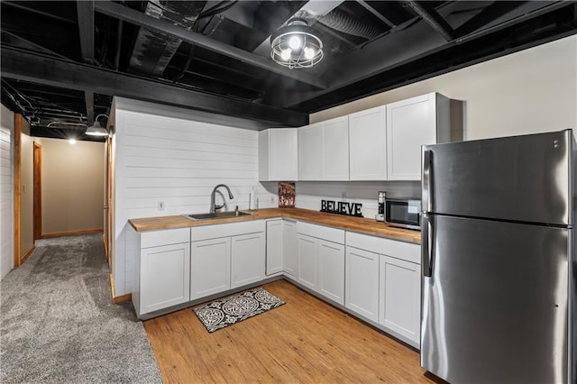 kitchen with butcher block counters, sink, white cabinetry, appliances with stainless steel finishes, and light hardwood / wood-style floors