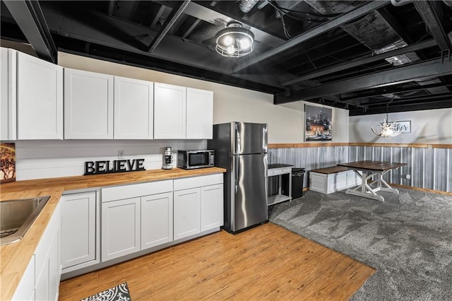 kitchen featuring stainless steel appliances, butcher block counters, sink, and white cabinets