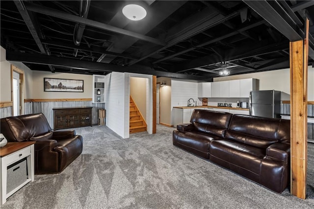 living room with sink, wooden walls, and carpet