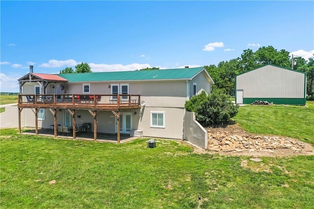 rear view of house with a wooden deck, a lawn, and a patio area