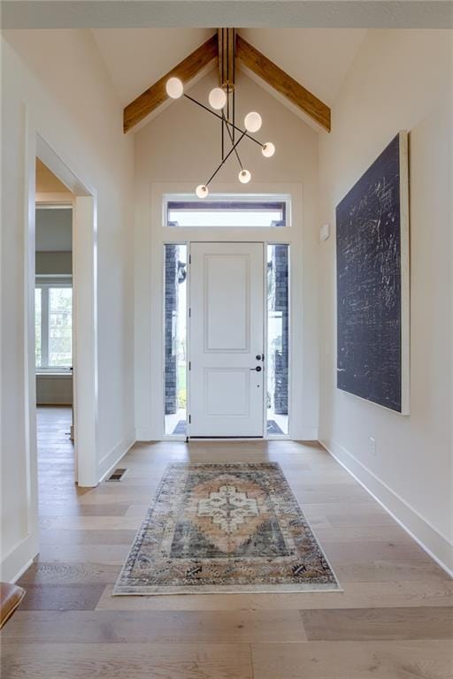 entryway featuring beam ceiling, a healthy amount of sunlight, and light hardwood / wood-style floors