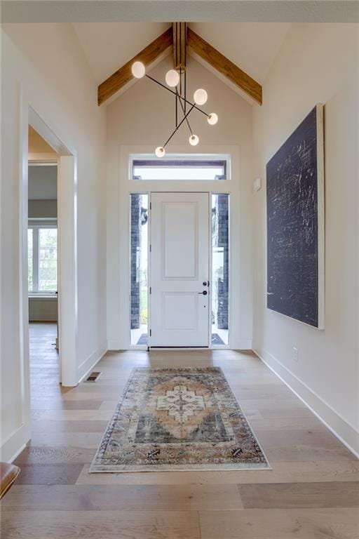 foyer featuring baseboards, lofted ceiling with beams, and wood finished floors