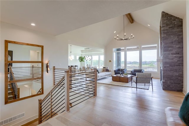 living room with beam ceiling, plenty of natural light, light hardwood / wood-style floors, and an inviting chandelier