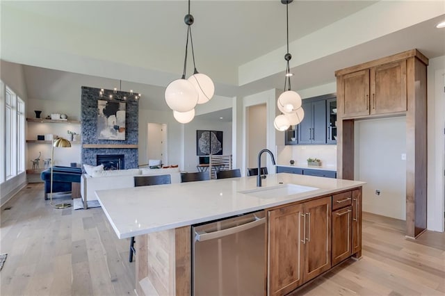 kitchen with light wood finished floors, dishwasher, open floor plan, and a sink