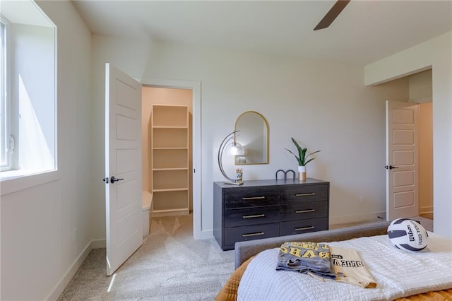 bedroom with a ceiling fan, a closet, baseboards, light colored carpet, and a spacious closet