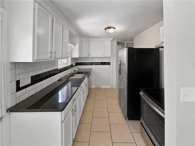 kitchen featuring decorative backsplash, white cabinets, light tile patterned flooring, and appliances with stainless steel finishes