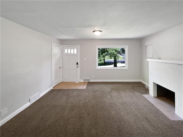 unfurnished living room with light carpet, a textured ceiling, and a fireplace