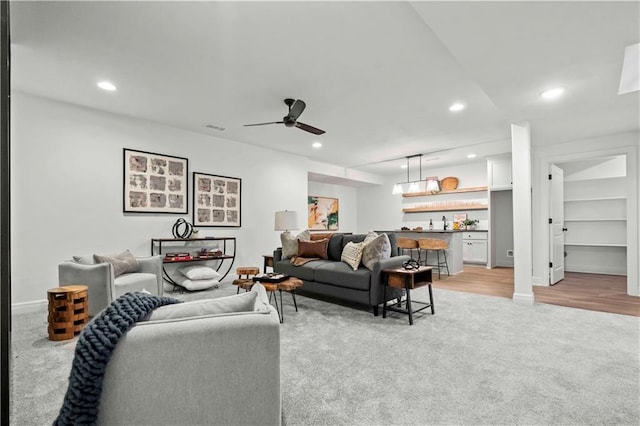 carpeted living room featuring wet bar and ceiling fan