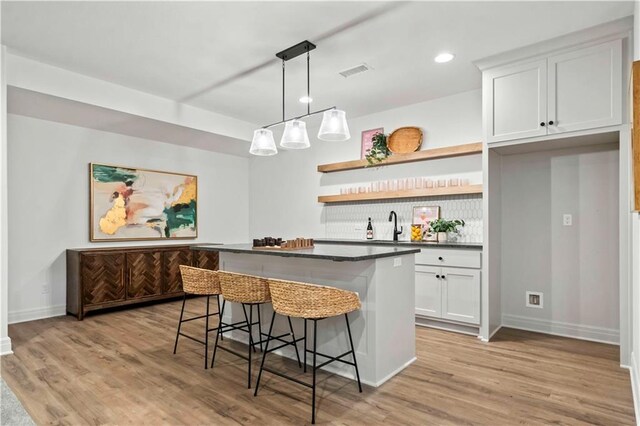 1600 SW 27th St, Lees Summit, MO 64082 - kitchen with open shelves, white cabinets, a breakfast bar, light wood-style flooring, and recessed lighting