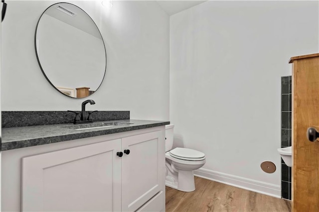 bathroom with hardwood / wood-style flooring, toilet, and vanity