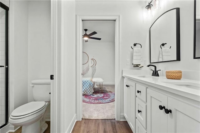 bathroom with ceiling fan, hardwood / wood-style flooring, toilet, a shower with shower door, and vanity