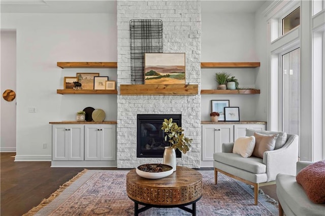 living area with a fireplace, built in shelves, and dark hardwood / wood-style floors