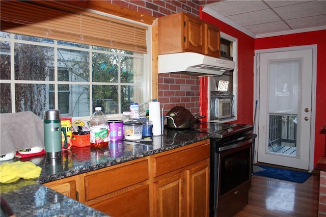 kitchen with dark stone counters, crown molding, and electric stove