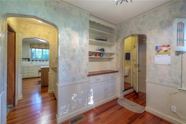 hallway with dark hardwood / wood-style flooring and ornamental molding