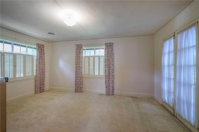 spare room featuring light colored carpet and a wealth of natural light