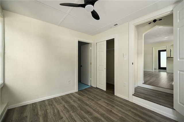 unfurnished bedroom featuring ceiling fan, a closet, and dark wood-type flooring