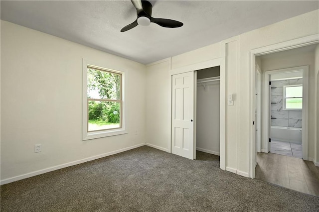 unfurnished bedroom with dark colored carpet, multiple windows, and ceiling fan