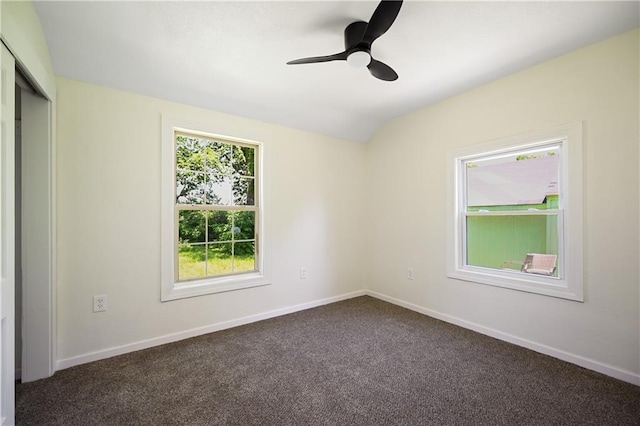 spare room featuring ceiling fan and dark carpet