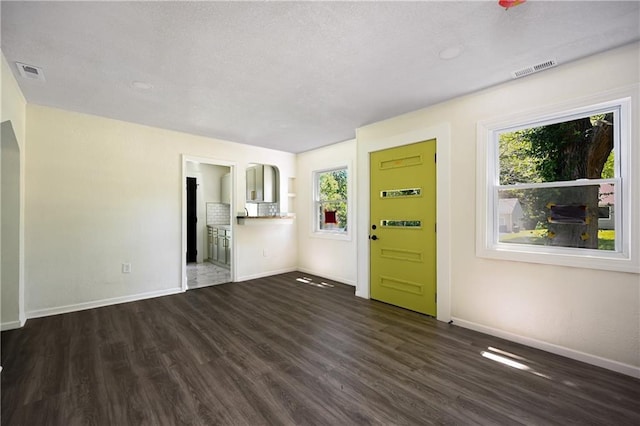 unfurnished living room featuring a textured ceiling, a wealth of natural light, and dark hardwood / wood-style floors