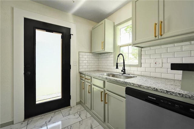 kitchen featuring tasteful backsplash, light stone counters, stainless steel dishwasher, sink, and cream cabinets