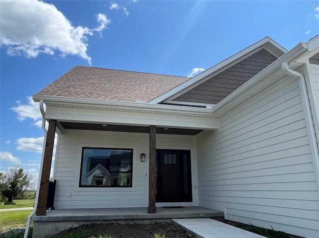 property entrance with a porch and roof with shingles