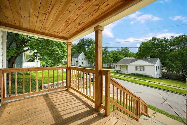 wooden terrace featuring a porch and a lawn