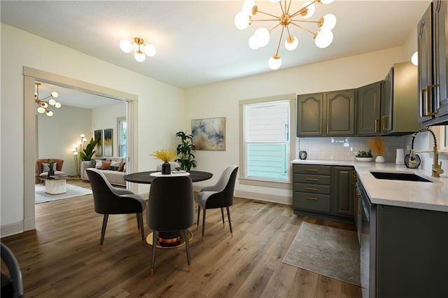 dining area with sink, dark wood-type flooring, and a notable chandelier