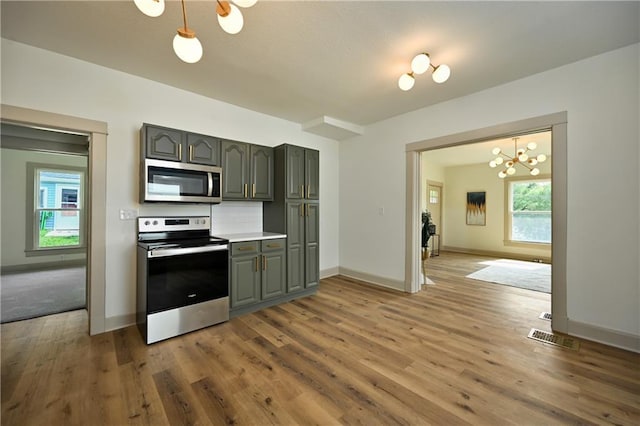 kitchen featuring hanging light fixtures, an inviting chandelier, stainless steel appliances, and hardwood / wood-style flooring