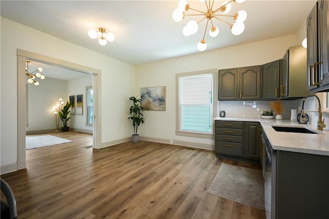 kitchen with decorative backsplash, hardwood / wood-style floors, a notable chandelier, and sink