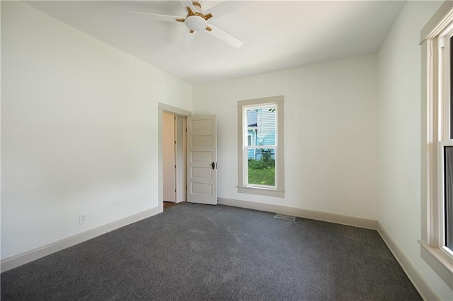 empty room with dark colored carpet and ceiling fan