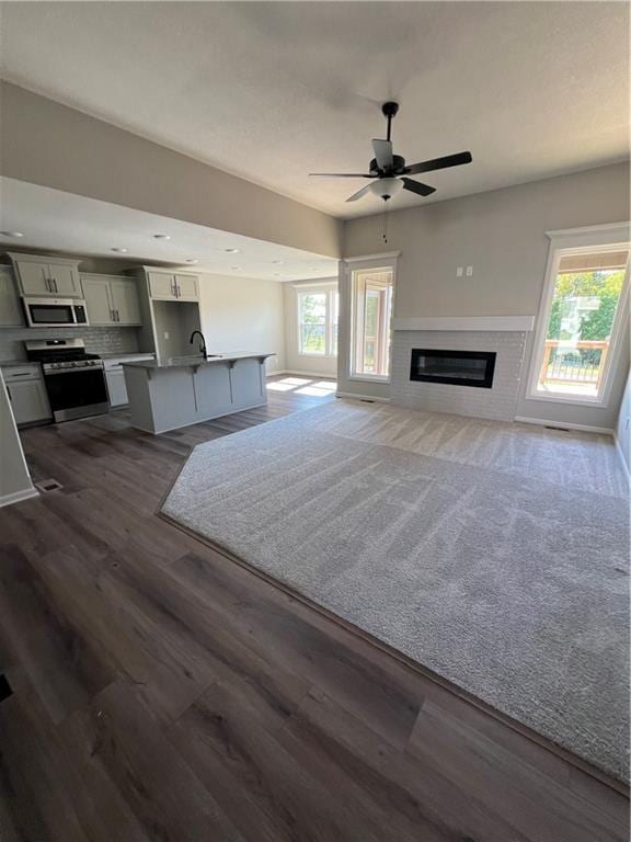 unfurnished living room with ceiling fan, sink, and dark hardwood / wood-style flooring