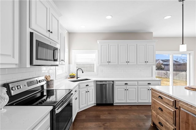 kitchen with pendant lighting, sink, appliances with stainless steel finishes, dark hardwood / wood-style floors, and white cabinets