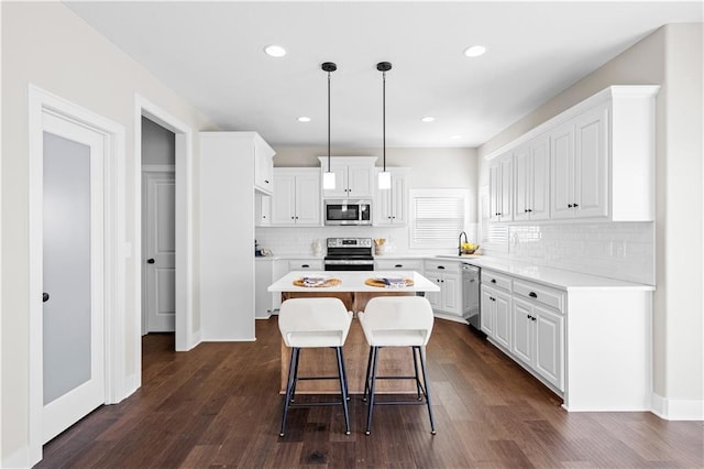 kitchen featuring pendant lighting, sink, appliances with stainless steel finishes, white cabinets, and a kitchen island