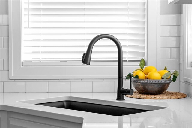 room details featuring tasteful backsplash, light stone countertops, and sink