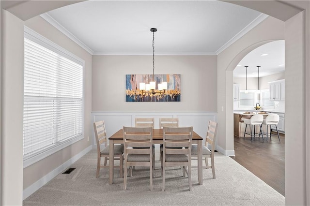 dining room with ornamental molding and a chandelier