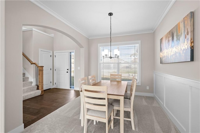 carpeted dining area featuring ornamental molding and a chandelier