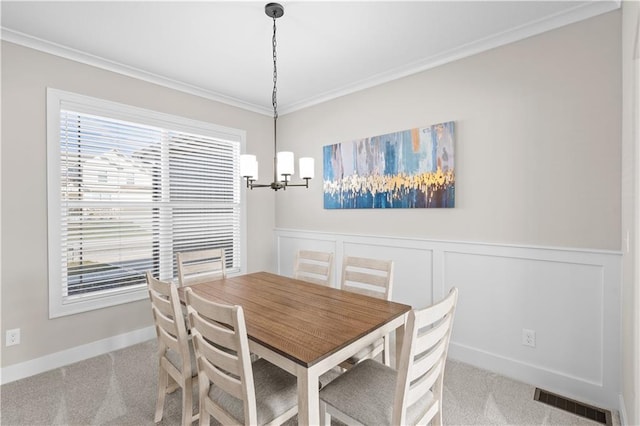 carpeted dining room featuring ornamental molding and a notable chandelier