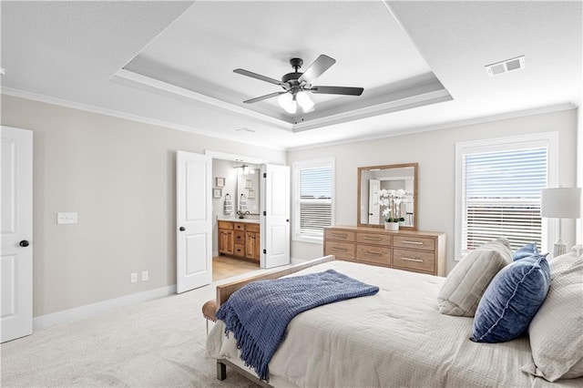 carpeted bedroom featuring a raised ceiling, crown molding, ensuite bathroom, and ceiling fan