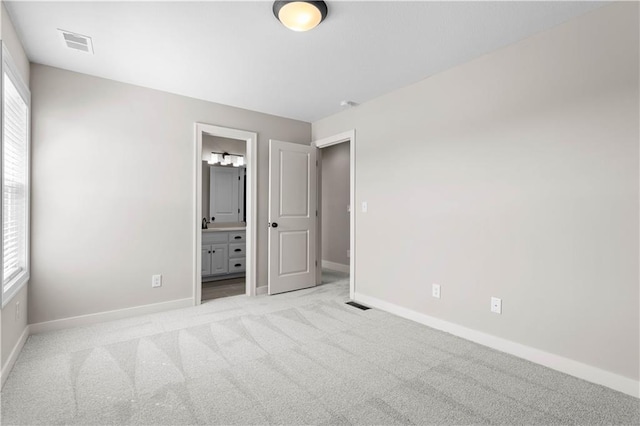 unfurnished bedroom with light carpet and connected bathroom