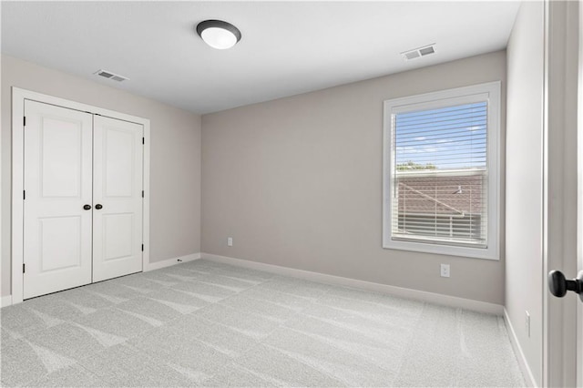 unfurnished bedroom with a closet and light carpet