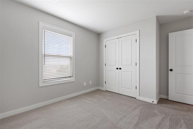 unfurnished bedroom with light carpet and a closet