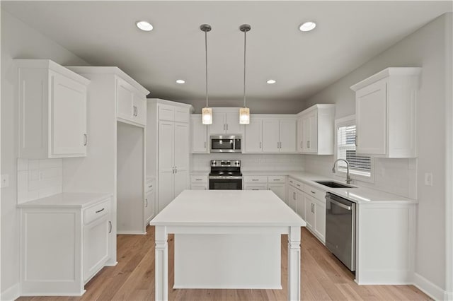 kitchen with white cabinetry, a center island, light hardwood / wood-style floors, and appliances with stainless steel finishes