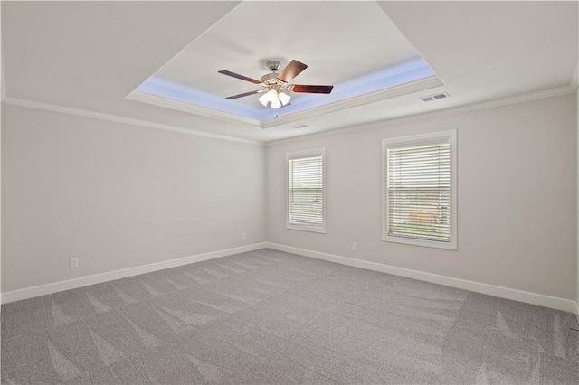 spare room with carpet, ceiling fan, crown molding, and a tray ceiling