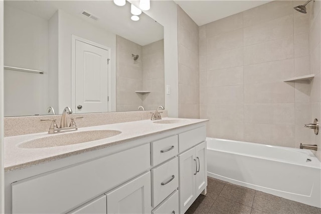 bathroom with tile patterned flooring, vanity, and tiled shower / bath