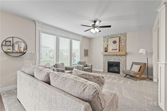 living room featuring light carpet, a stone fireplace, and ceiling fan